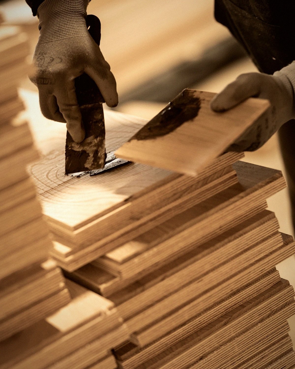 A gloved hand fills a knot in a Classic-grade oak board at the mill
