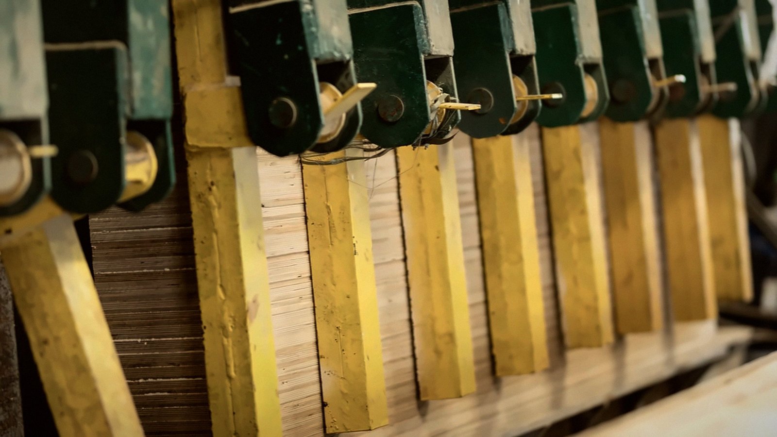 A press with green clamps bonding oak top layers to plywood cores at the mill