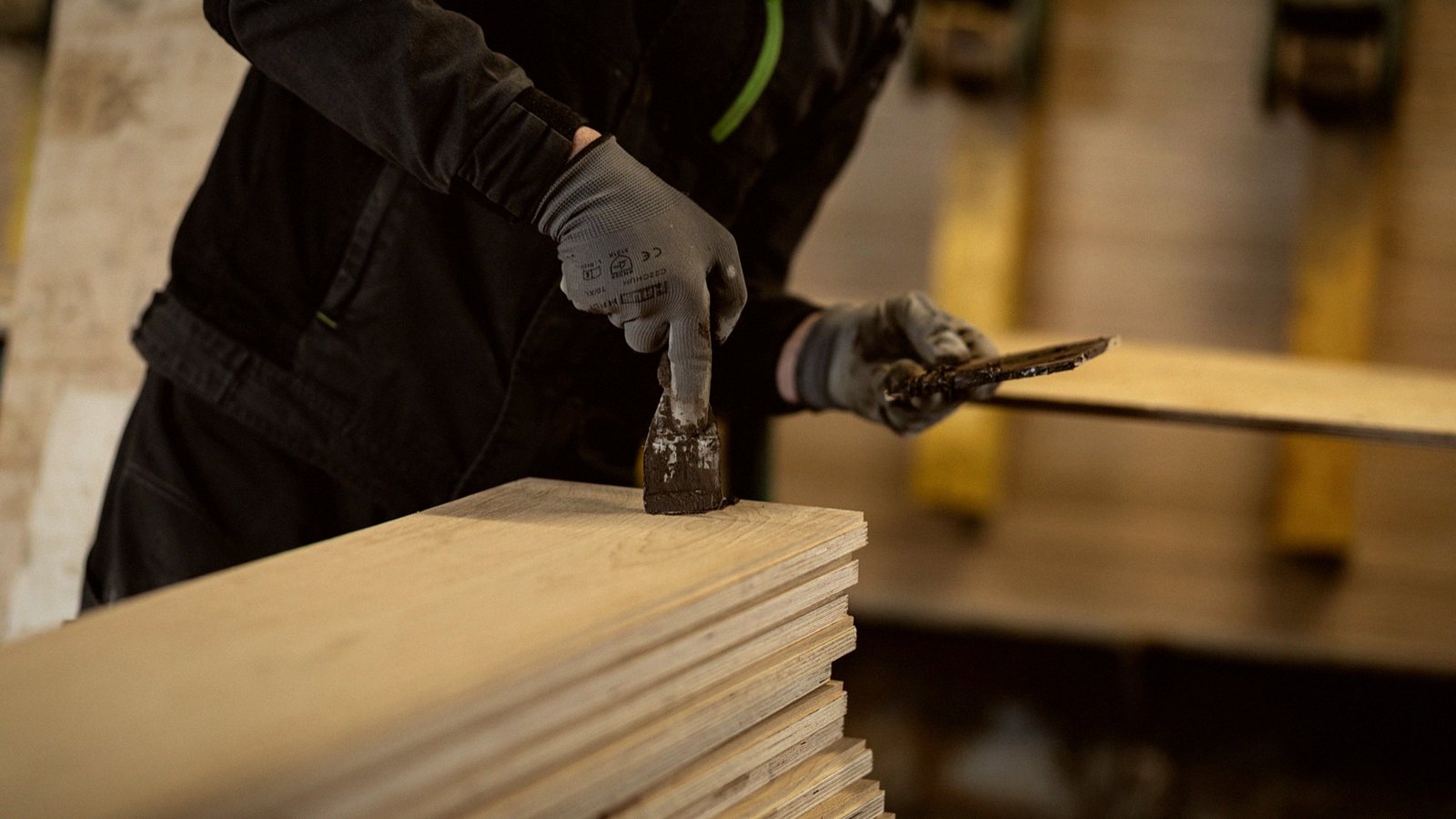 A worker in gloves works the face of an oak board