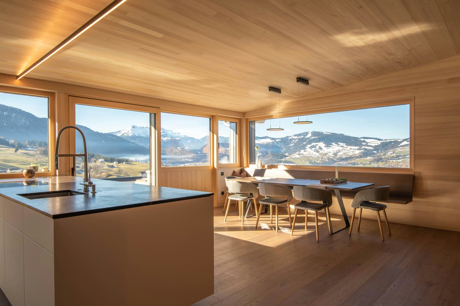 A spacious timber interior overlooking the mountains, with natural wood floors and broad windows