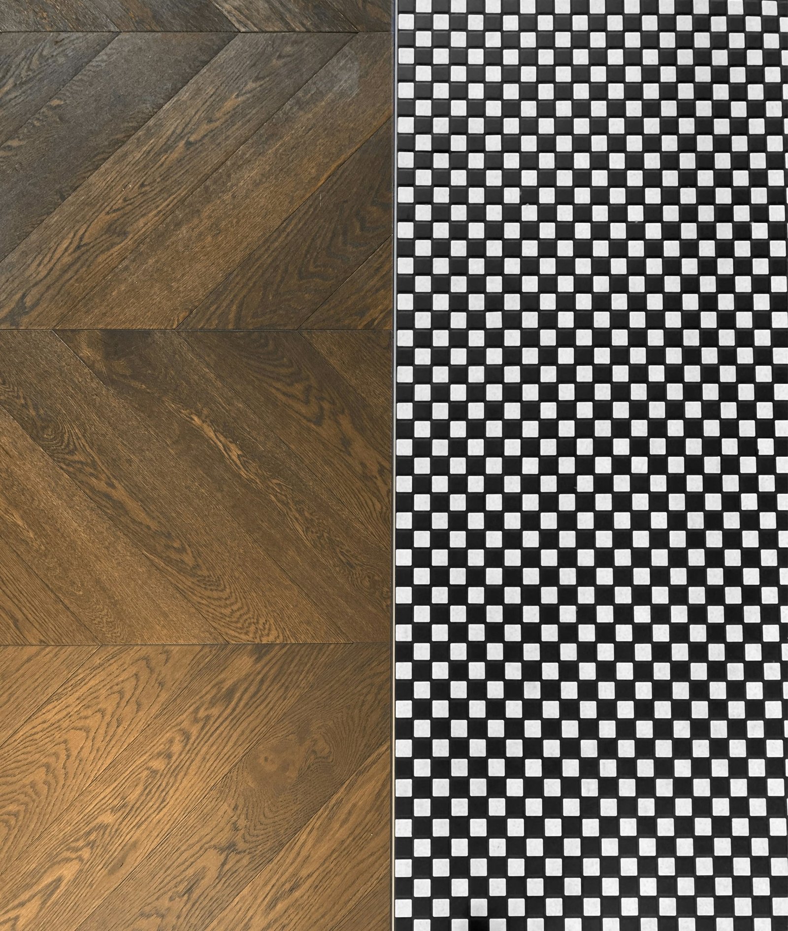 A chevron wood floor meets a small black and white tile pattern