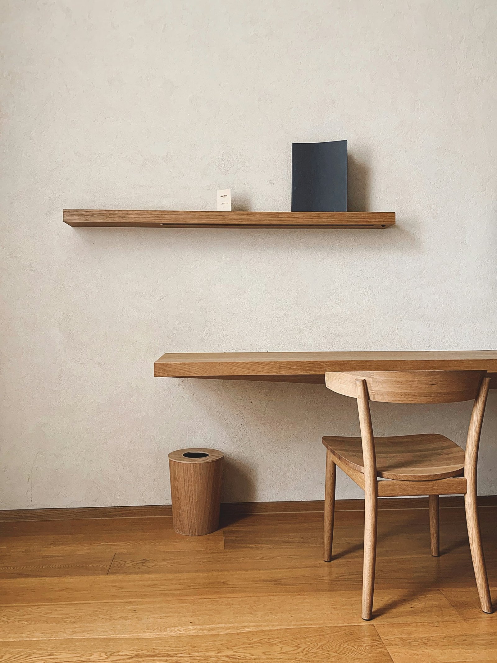 A simple wood desk and chair in a quiet room with a warm wood floor