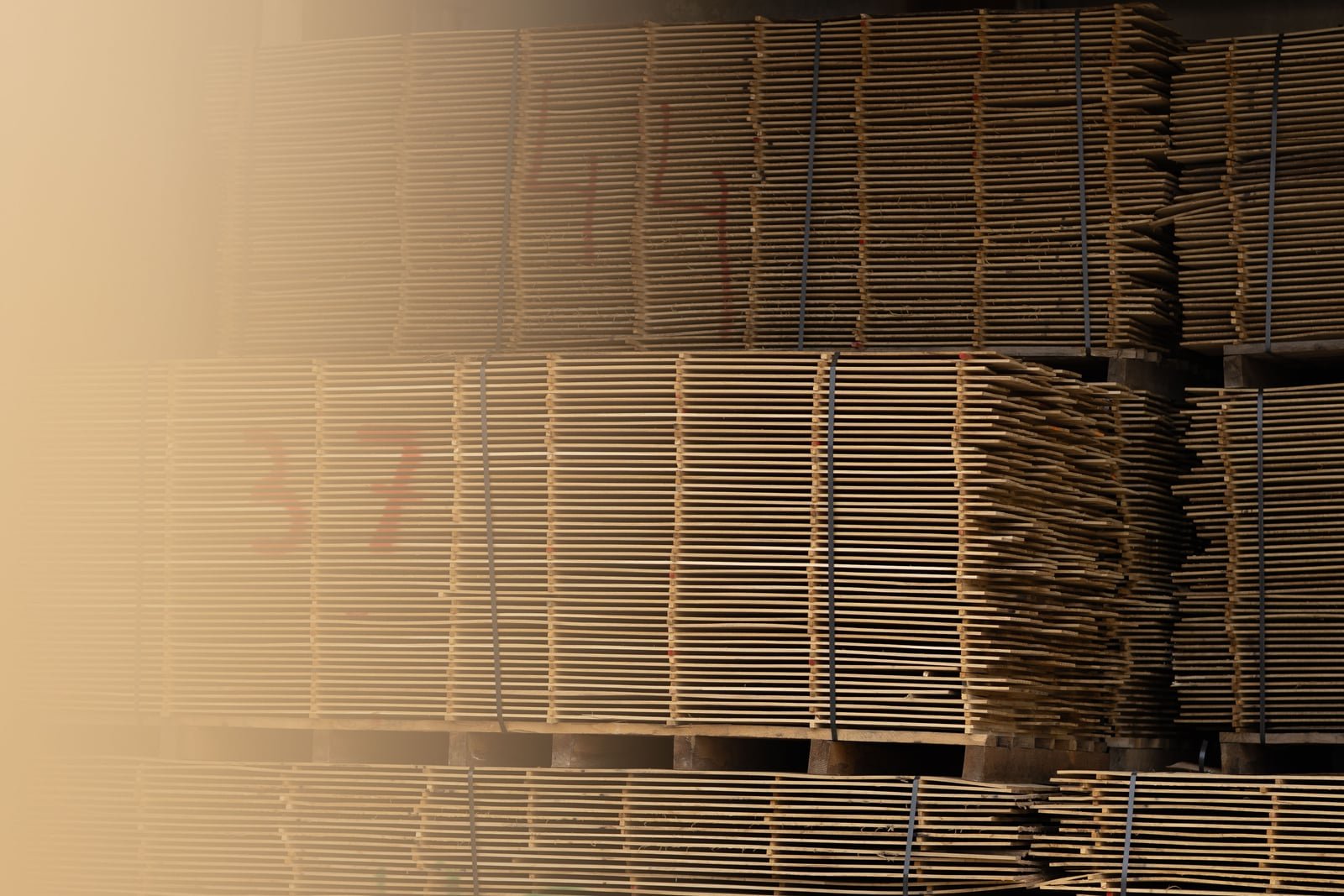 Thin dried oak lamellae stacked in closely spaced layers at the mill